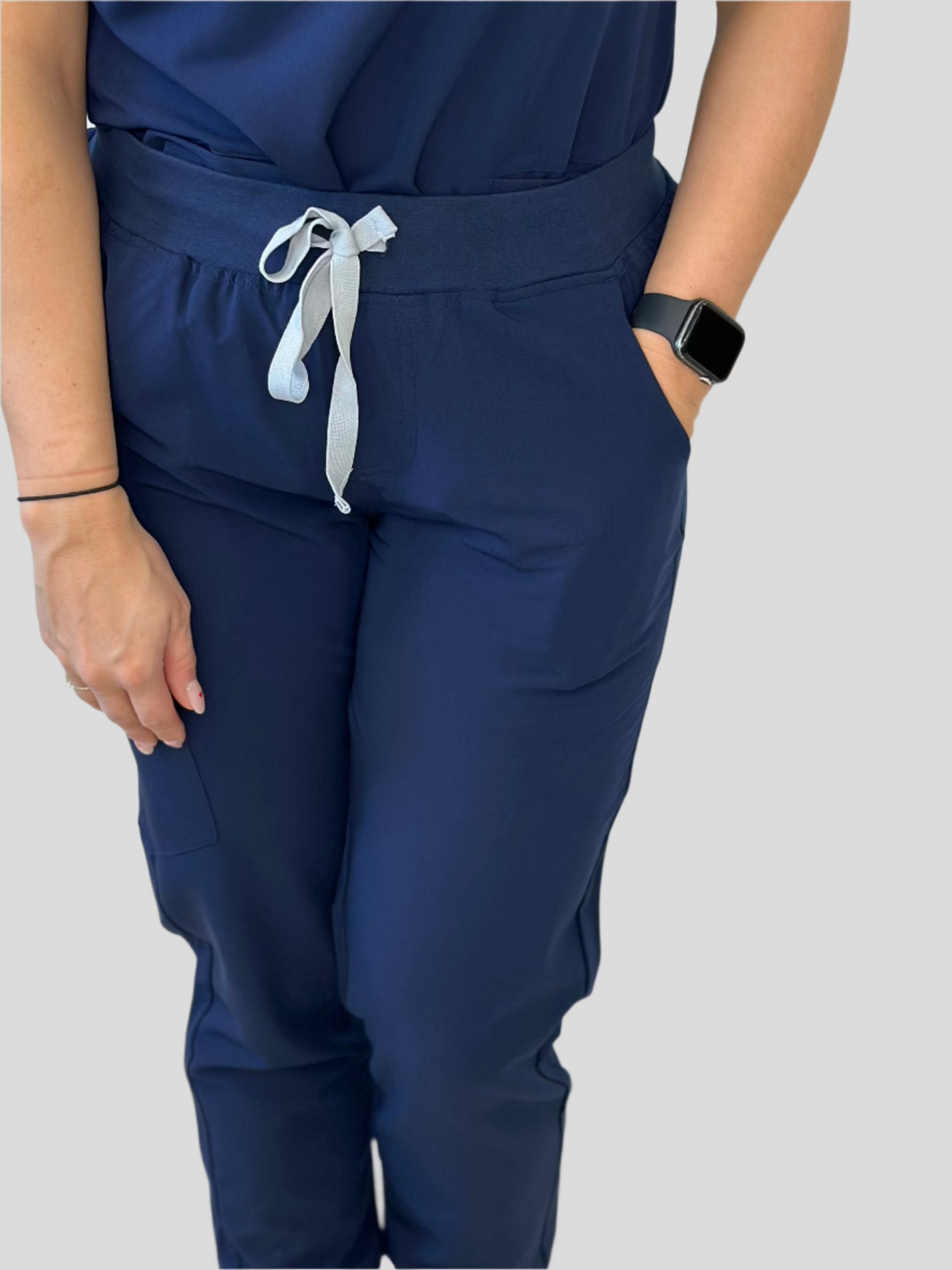 A person wearing navy blue scrub joggers with an adjustable drawstring waistband, side pockets, and elastic cuffed ankles.